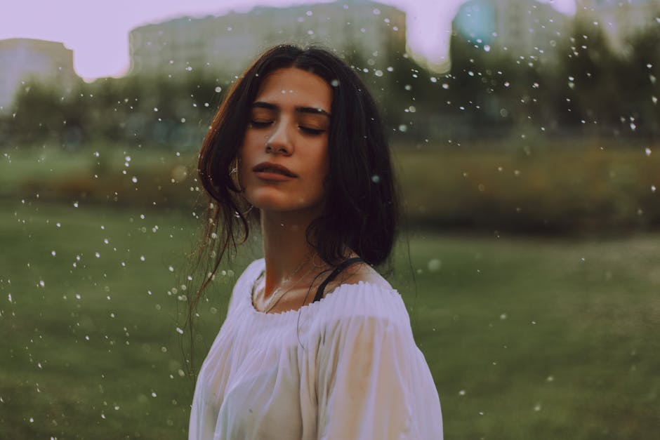 Serene portrait of a young woman enjoying the outdoors, with gentle rain falling, oily skin